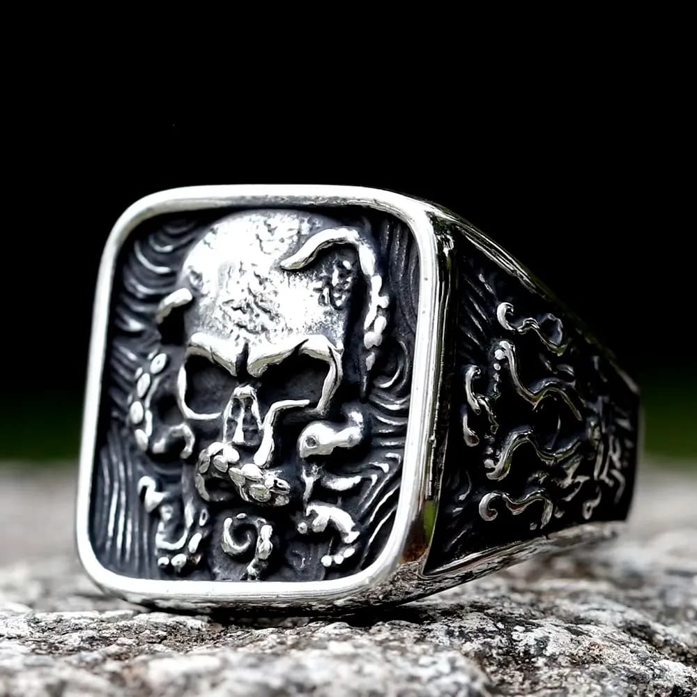 Square-faced 316L stainless steel ring featuring a detailed skull relief surrounded by swirling organic patterns on the face and sides, with polished raised areas and darkened recesses.