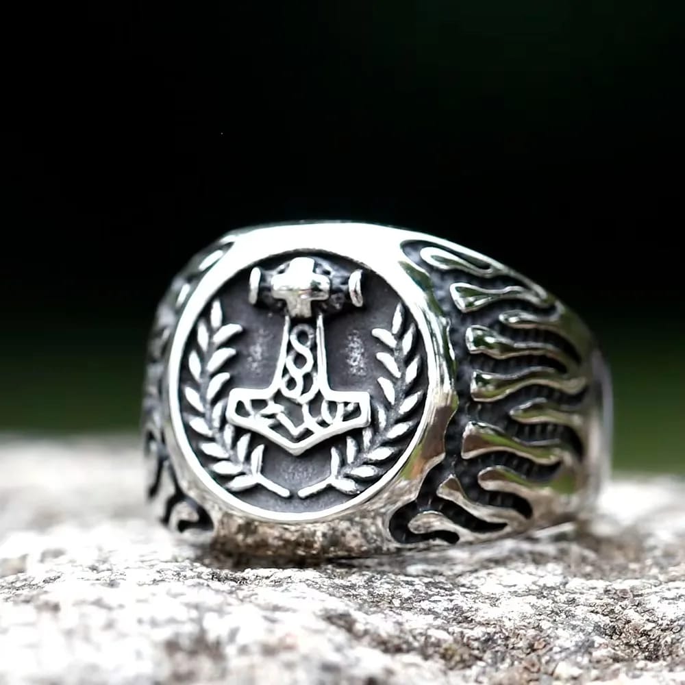 Stainless steel ring with an etched Mjolnir surrounded by a laurel wreath on the face, and wavy patterns on the sides, featuring a polished and antique finish.