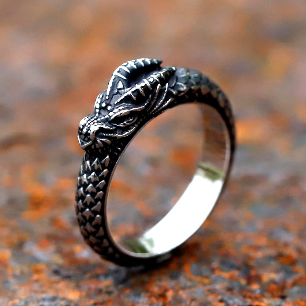 Detailed 316L stainless steel Nordic dragon ring on a rustic surface.