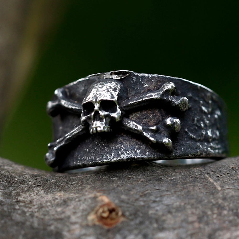 Close-up of a vintage 316L stainless steel men's ring featuring a skull and crossbones design, resting on a rustic wooden surface.