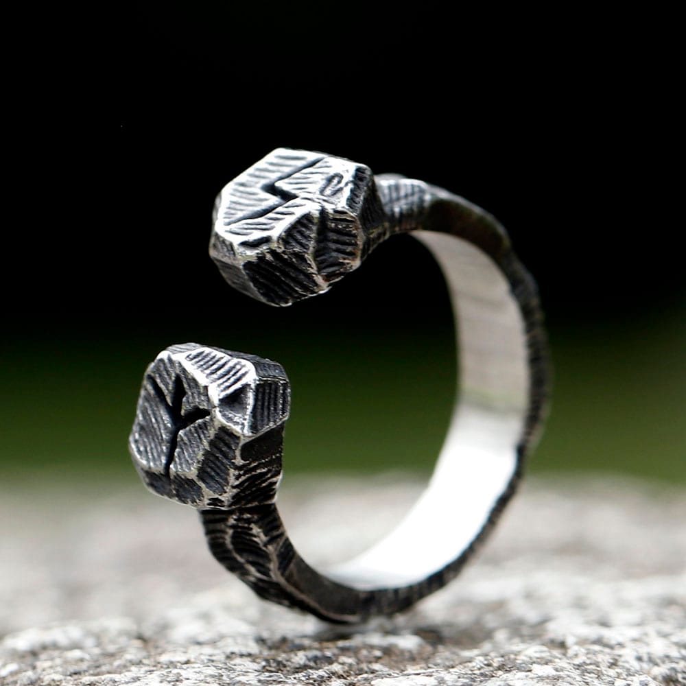 Close-up of engraved Norse rune terminals on textured stainless steel ring