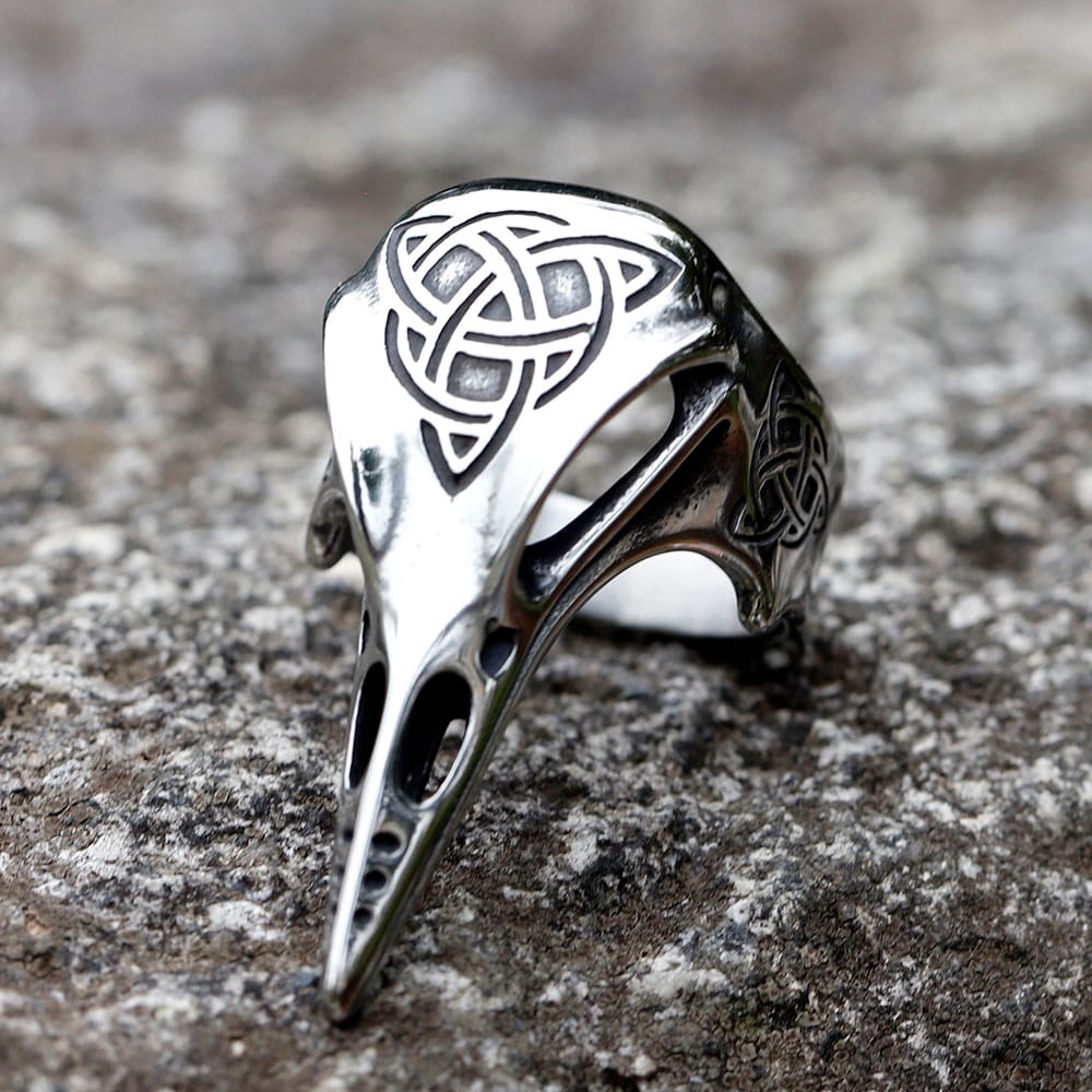 Celtic knot raven skull stainless steel ring resting on a textured stone surface