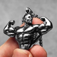 Frontal view of the stainless steel bodybuilder pendant, highlighting the detailed physique, held by fingertips