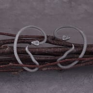 Pair of stainless steel snake non-piercing ear cuffs resting on natural branches