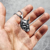 Frontal close-up of the Hannya mask pendant, showing eyes, nose, and mouth details.