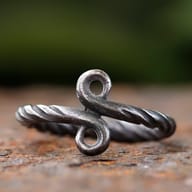 Full side view of the 316L stainless steel Troll Cross ring on a rusted surface.