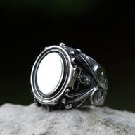 Front three-quarter view of men's Gothic skull signet ring in 316L stainless steel resting on a stone