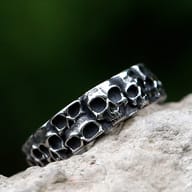 Close-up of multiple skull motifs intricately carved on the exterior of the steel ring.