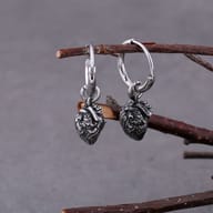 Pair of gothic anatomical heart drop hoop earrings hanging from a twig