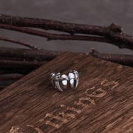 Detailed view of one 316L stainless steel Gothic Vampire Teeth ear cuff in wood shavings.