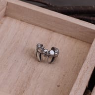 Partial view of a 316L stainless steel ear cuff against a dark, textured background.