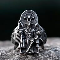 Detail of the Baphomet ring's top, focusing on the pentagram and goat head, with blurred green background.