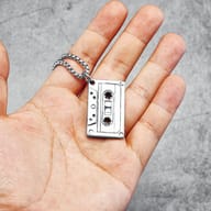 Close-up of polished stainless steel cassette tape pendant with chain detail