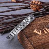 Close-up of the detailed golden Thor's hammer and woven Celtic knot pattern on the steel band