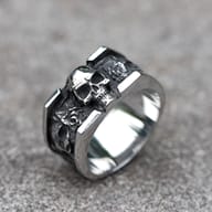 Men's 316L stainless steel vintage skull ring, featuring a prominent skull and side engravings, displayed on a concrete surface.