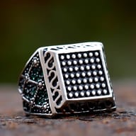 Angled perspective showcasing the oxidized antique finish and green zircon side detailing