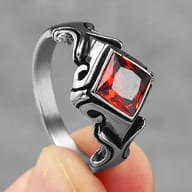 Stainless steel ring from an angled perspective, focusing on the dark, oxidized details of the design.