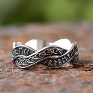 Close-up of the Viking runes on the stainless steel ring band against a blurred green background.