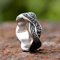 Detailed view of the interwoven bands and etched runes on the stainless steel ring's surface.