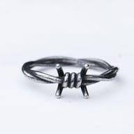 Close-up of a rustic 316L stainless steel barbed wire ring on a white background.