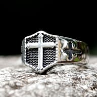 Close-up of the polished 316L stainless steel signet ring face with an embossed cross and textured background.
