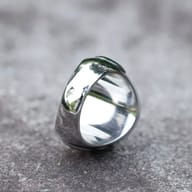 Detailed view of the compass rose on a 316L stainless steel men's ring, highlighting the cardinal points and star, against a blurred green background.