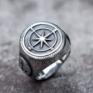 Overhead shot of the men's stainless steel ring, emphasizing the circular compass rose and the ring's robust form.