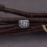 Detailed view of 316L stainless steel skull pattern ear cuff on dark branches.