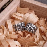 Close-up of two 316L stainless steel skull pattern ear cuffs on dark branches.