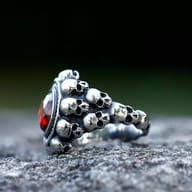 Side view of the stainless steel skull ring, showing the textured band adorned with multiple small skulls.