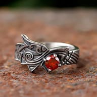 Close-up detail of the red zircon stone set as the dragon's eye in the ring