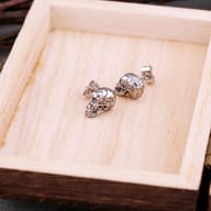 Close-up detail of cracked skull stud earring showcasing fissure textures and open jaw