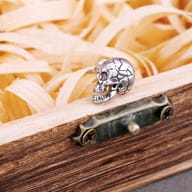 Pair of cracked skull stud earrings resting together on a wooden surface