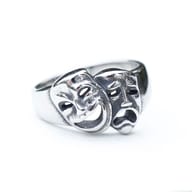 Macro shot of the smiling drama mask on the stainless steel ring, showing the open mouth and cheerful eye expression.