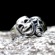 Angled view of the polished 316L stainless steel Cry and Smile ring, highlighting the detailed smiling mask with its hollow eyes and mouth.