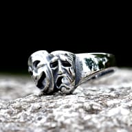 Side profile of the 316L stainless steel drama mask ring, showing the band's thickness and the intricate relief of the crying mask.