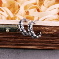 Detailed close-up of embossed skulls on stainless steel huggie earrings