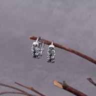 Both stainless steel skull earrings resting together on a rustic surface