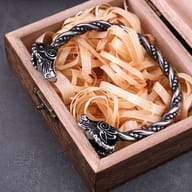 Close-up of intricately carved goat head terminals on stainless steel torc bracelet
