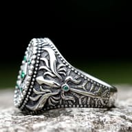 Close-up of the vintage pattern and central square green gemstone on a men's stainless steel ring.
