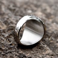Angled shot of the stainless steel ring, showcasing the Tree of Life and intricate side band patterns.
