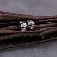 Angled perspective of both gothic skull earrings displaying metallic finish and red accent stones