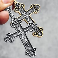 Detailed view of the Jesus figure on the crucifix, with carved symbols, held by a finger.