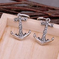 Close-up detail of ornate filigree carving on stainless steel anchor earring charm