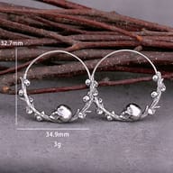 Pair of antique finish stainless steel skull hoop earrings on a neutral background