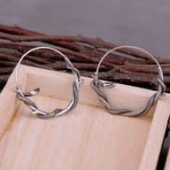 Stainless steel gothic snake hoop earrings resting on a neutral background