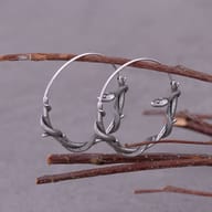 Pair of gothic stainless steel snake hoop earrings hanging on a small branch