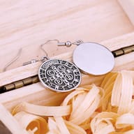 Close-up of one 316L stainless steel Saint Benedict Medal drop earring, highlighting the detailed engraving and fish hook.