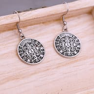 Pair of 316L stainless steel Saint Benedict Medal drop earrings displayed on a light wooden surface.