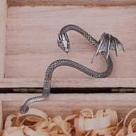 Close-up of sculpted dragon head and textured wing on stainless steel ear cuff
